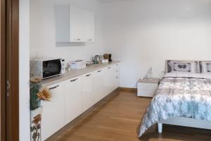 a bedroom with a bed and a kitchen with white cabinets at LA VELA in Negrar