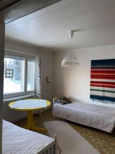 Cette chambre comprend 2 lits, une table et une fenêtre. dans l'établissement Omakotitalo Simojärvellä, à Ranua