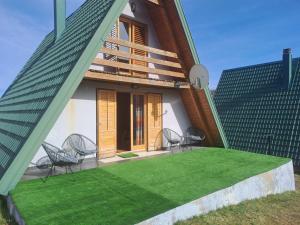 a house with chairs and a green lawn at Gorska vila in Žabljak