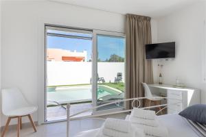a bedroom with a bed and a desk and a large window at Villa Greca Holiday Rooms in Sant' Isidoro