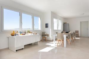 cocina blanca con mesa, sillas y ventanas en Villa Greca Holiday Rooms, en Sant' Isidoro