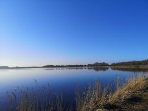 uma vista para um lago com um céu azul em Ferienwohnung Jasmin - a53959 em Maasholm-Bad