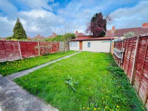 a backyard with a fence and green grass at The European 3 Bedroom House By AltoLuxoExperience Short Lets & Serviced Accommodation With Free Parking in Bristol