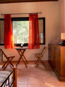 Cette chambre dispose d'un bureau et d'une fenêtre avec des rideaux rouges. dans l'établissement Cozy Anthousa House with Sea View, à Anthoúsa