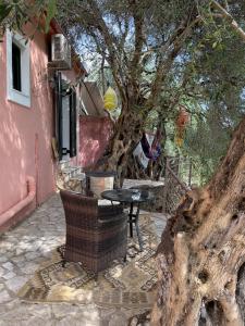 une table et une chaise sous un arbre à côté d'une maison dans l'établissement Cozy Anthousa House with Sea View, à Anthoúsa