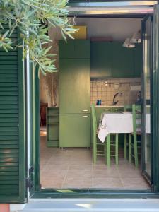 une cuisine avec des placards verts et une table avec des chaises dans l'établissement Cozy Anthousa House with Sea View, à Anthoúsa