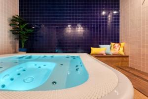 a jacuzzi tub in a bathroom with purple tiles at Casa Mila Loire - L'expérience Hôtel & Spa - Angers Saumur in Saint-Mathurin