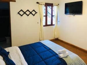 a bedroom with a bed with a blue blanket and a television at HOTEL RUTA 40 VILLA DE LEYVA in Villa de Leyva