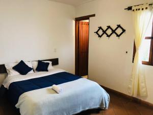 a bedroom with a large bed with blue and white sheets at HOTEL RUTA 40 VILLA DE LEYVA in Villa de Leyva