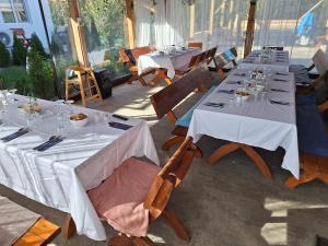 a dining room with tables and chairs with white tablecloths at Cabana Casa Dia in Sadu