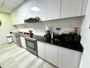 cocina con armarios blancos y encimera negra en Dubai Marina - 5 bedroom, resort feel, great Amenities, en Dubái