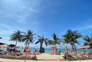 a beach with chairs and palm trees and the ocean at Koh Chang Resort in Ko Chang
