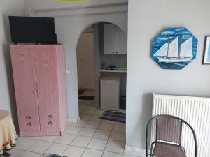 a living room with a pink cabinet and a tv at Marilena Rooms Plataria in Plataria