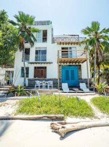 a white house with two chairs and palm trees at Casa Tinti Hotel Boutique in Tintipan Island