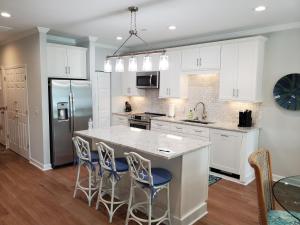 a kitchen with white cabinets and a large island with bar stools at The Moorings Condo - Wild Dunes Resort - Isle of Palms Marina in Isle of Palms
