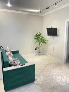 a living room with a green couch and a tv at ЖК Еламан уютная евродвушка in Almaty +4 photos