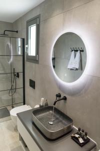 a bathroom with a sink and a toilet and a mirror at Anthelia Luxury Villas in Karpathos Town