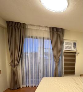 1 dormitorio con cama y ventana en Resort-inspired Condo with Queen-size bed & 50-inch Smart TV, en Cebú