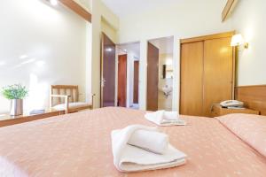 a bedroom with a large bed with towels on it at CiTYZen Hotel in Loutraki