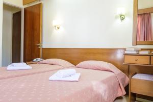 um quarto com duas camas cor-de-rosa com toalhas em CiTYZen Hotel em Loutraki