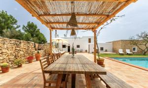 une table et des chaises en bois sur une terrasse avec une piscine dans l'établissement CAN FERRER Authentic payesa house, à Sant Antoni de Portmany