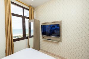 um quarto com uma televisão na parede e uma janela em Rihanna Hotel Apartment em Kuwait