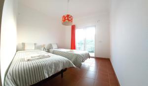 two beds in a room with a window at Ocean & Nature Flat - Aljezur - Algarve West Coast - 1,6km Praia Monte Clérigo in Aljezur