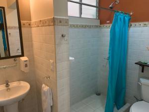 a bathroom with a blue shower curtain and a sink at Casa de Lis Hotel & Tourist Info Centre in Turrialba