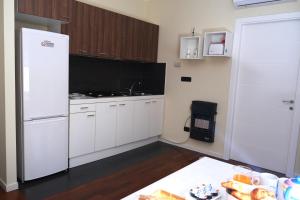 La cuisine est équipée de placards blancs et d'un réfrigérateur blanc. dans l'établissement Apartment Nadia, à Naples