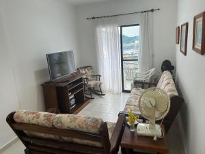 a living room with a couch and a tv at Apartamento - Jardim Marina in Mongaguá