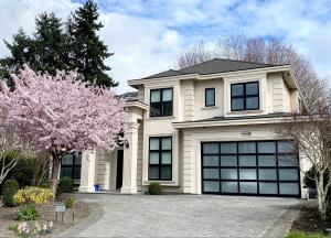 a white house with black windows and a tree at Vancouver Shangrila House in Richmond