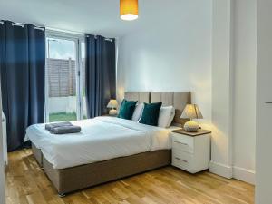 a bedroom with a bed with blue curtains and a window at Deluxe 3 Bed Flat with garden in Finchley