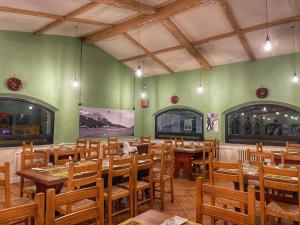 a restaurant with wooden tables and chairs and green walls at Hotel Lo Sciatore in San Massimo
