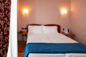 um quarto com uma cama com duas mesas e dois candeeiros em SIRIOHotel em Dormelletto