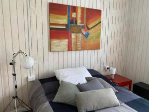 1 dormitorio con 1 cama con una pintura en la pared en Hostel Cala 816 en Frutillar