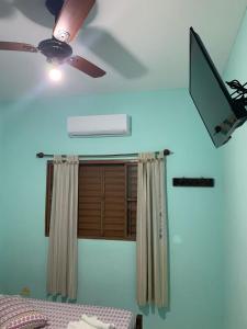 a ceiling fan and a window in a room at Pousada Morada dos Pássaros in Caraguatatuba