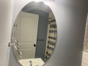 a bathroom mirror with a sink and a white door at Cozy get-away suite in Regina