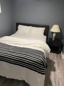 a bed with a black and white blanket and a lamp at Cozy get-away suite in Regina