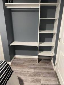 a closet with white shelves in a bedroom at Cozy get-away suite in Regina