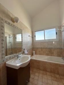 a bathroom with a tub and a sink and a bath tubermottermott at Villa Demetra, Coral Bay in Coral Bay