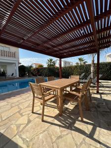 a wooden table and chairs under a wooden pergola at Villa Demetra, Coral Bay in Coral Bay