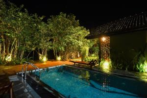 a swimming pool in front of a house at night at Pivithuru River Cabanas in Hikkaduwa