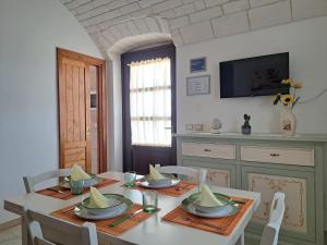 une salle à manger avec une table, des chaises et une télévision dans l'établissement Fogliantica Azienda Agrituristica, à Ceglie Messapica
