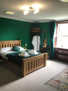 a bedroom with a large bed with green walls at Mansefield Rooms in Lockerbie