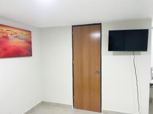 Habitación con puerta y TV en la pared en Posada Vacacional Brisas del Mar en Mazatlán