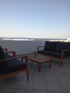 3 sedie e un tavolo sul balcone con vista sull'oceano di IFESTIA HOUSE ad Agia Paraskevi