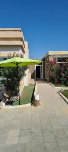 un paraguas verde y un banco frente a un edificio en Aram luxurious five bedroom villa with pools & fountains, en Sohar
