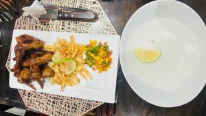 a plate of food with chicken and french fries on a table at Shafas Guest House in Rundu