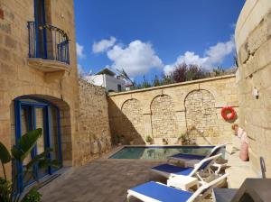 a swimming pool in a stone building with chairs around it at Il Hnejja Farmhouse in Mqabba