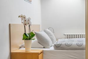 a white vase with white flowers on a bed at Apartmány Rozárka Turnov in Turnov